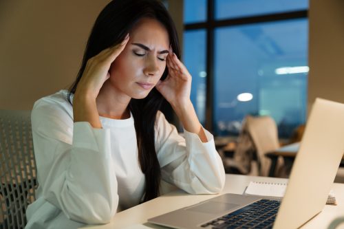 young businesswoman touching her temples having a headache in office