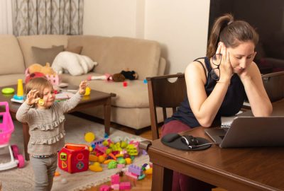 Tired mother trying to work on a laptop at home during her kid crying. Childcare and working mom concept.
